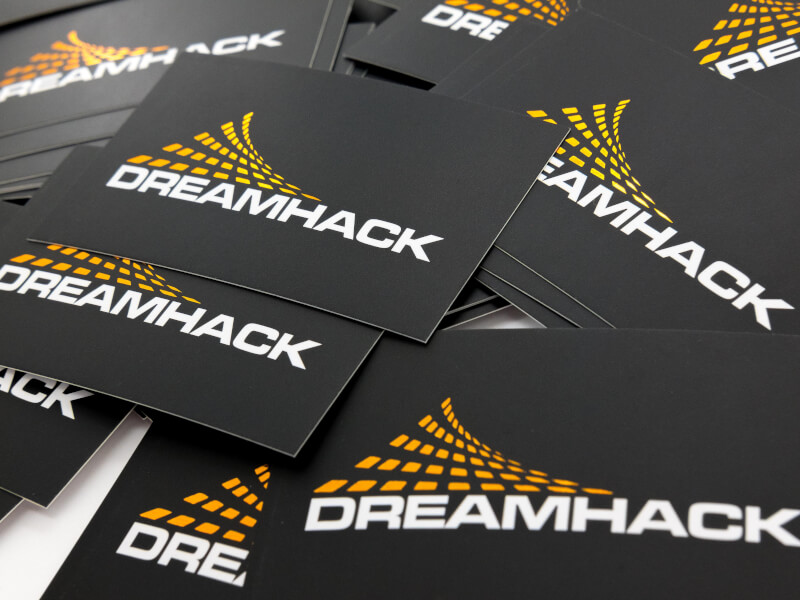 Bild på svarta visitkort för Dreamhack. Bakgrunden är svart och logotypen som är tryckt på kortet är i orange folie.