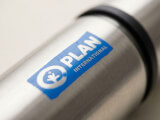 Närbild på tampotryck av Plan International-logotyp på rostfritt stål Termos Original