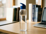 Tampotryckt vattenflaska sky klar med blått flip-lock i Tritan fotograferad på föreläsningsbord i akademisk miljö